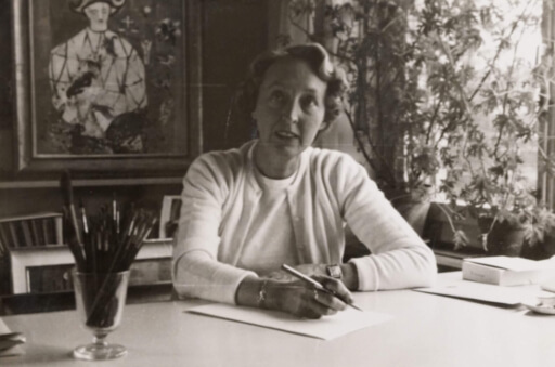 Portrait von Marguerite Ammann am Schreibtisch sitzend